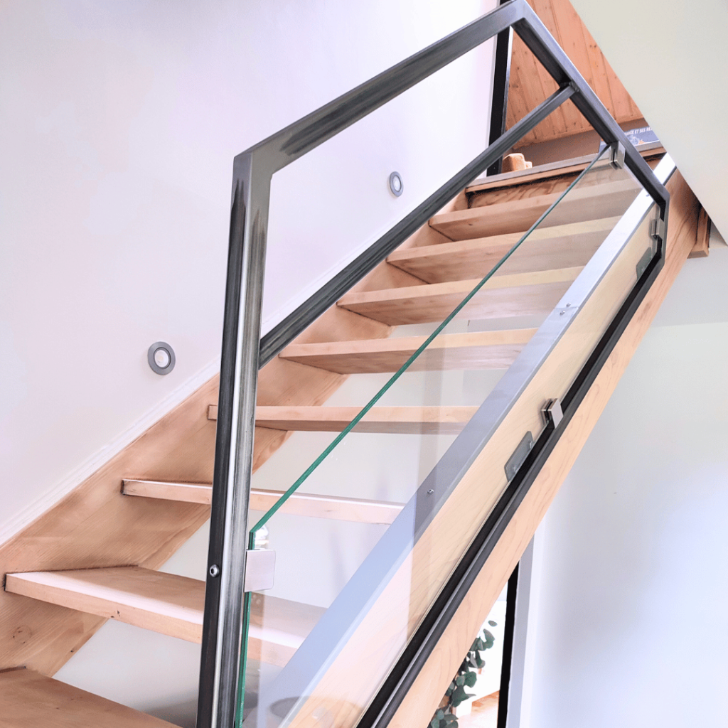 Garde-corps sur-mesure pour escalier intérieur en verre et acier brut verni fabriqué artisanalement dans le Haut-Doubs.