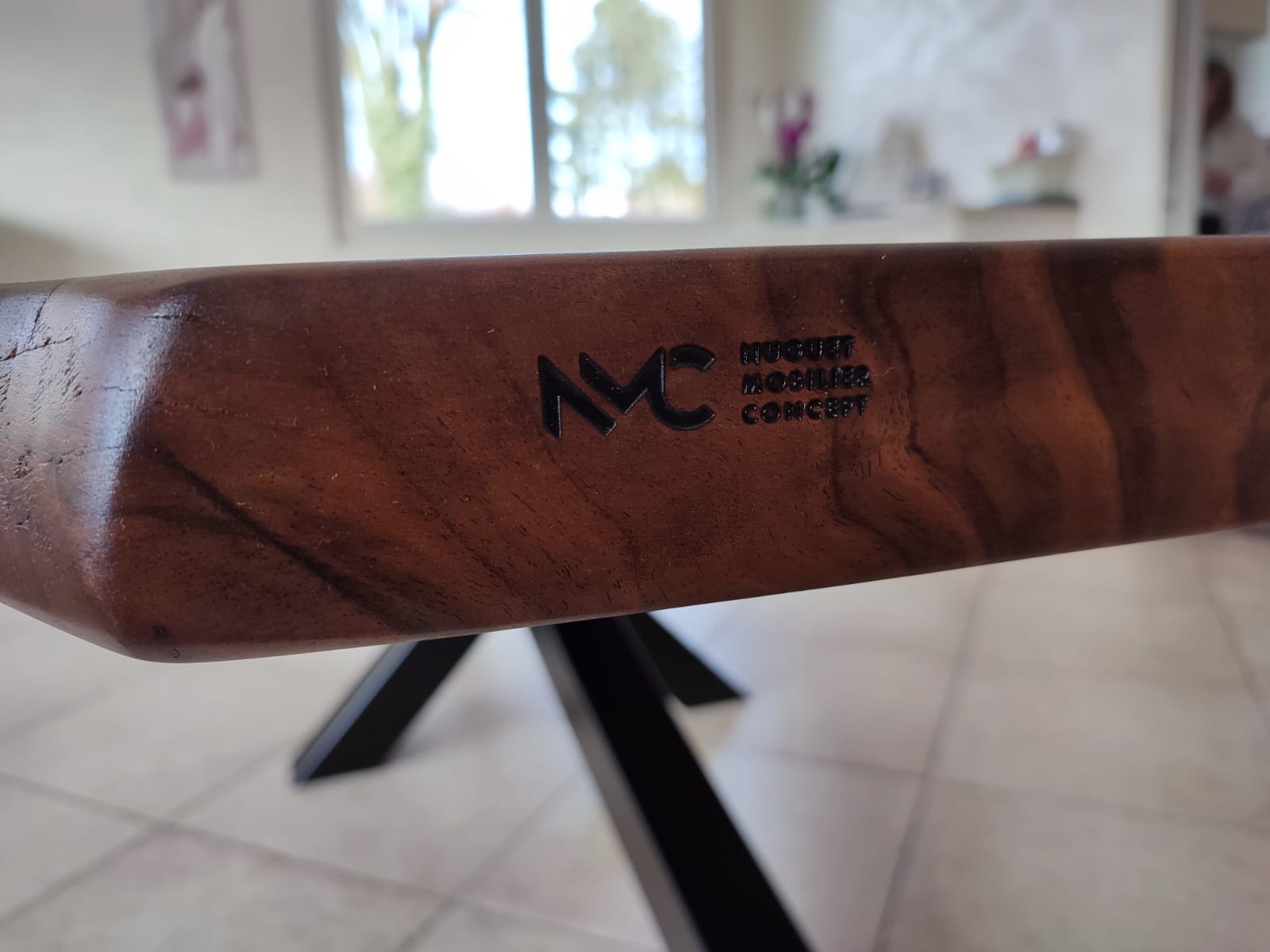 Logo NMC apposé sur le bord de cette table d'exception en noyer massif